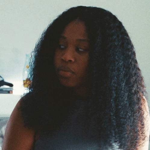 a woman with long curly hair looks to the side