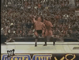 two wrestlers are fighting in a ring with a crowd in the background .