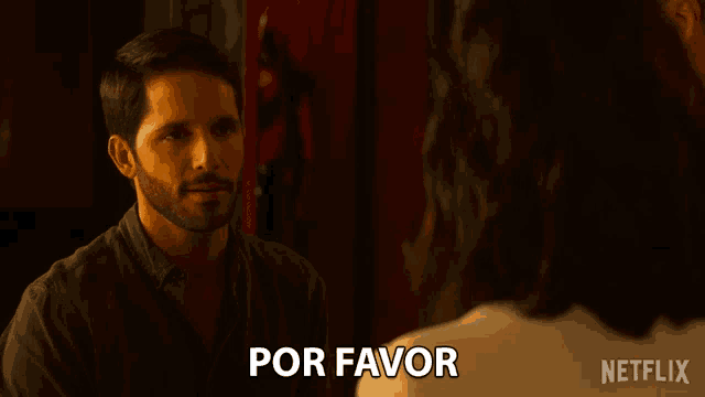 a man talking to a woman with the words por favor written on the back of his shirt