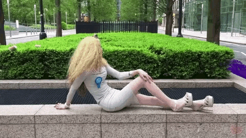 a woman in a white dress and high heels is laying on a wall .