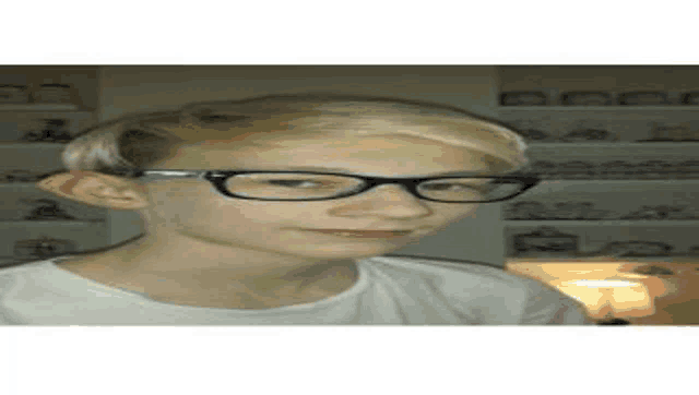 the boy is wearing glasses and a white shirt .