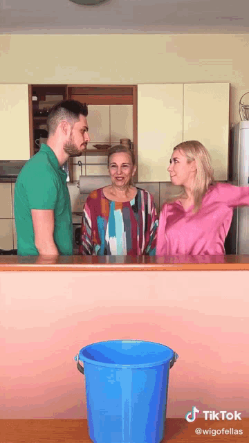 a man and two women are standing in front of a blue bucket that says tik tok