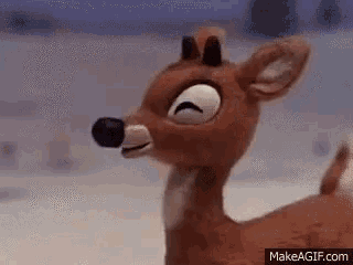 a close up of a stuffed reindeer with its eyes closed standing in the snow .