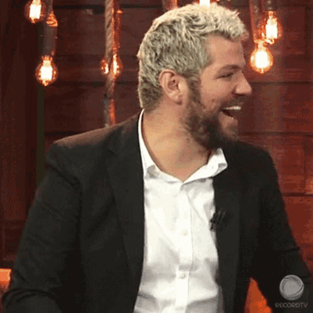 a man with a beard is laughing in front of a sign that says record tv