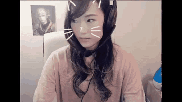 a woman wearing headphones and a cat face on her face is sitting in a chair .
