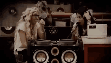 two women are sitting at a table with a microphone and a laptop .