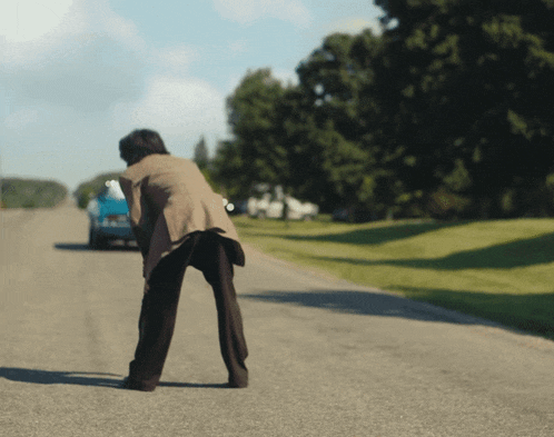 a person standing on the side of a road looking at a car
