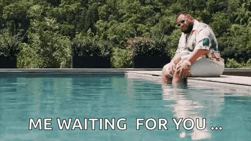 a man is sitting on the edge of a swimming pool with the words " me waiting for you " above him .
