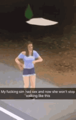 a woman in a blue shirt and shorts is standing on a sidewalk with a flying object in the background ..