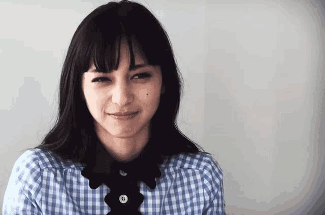 a woman wearing a blue and white checkered shirt has a black collar