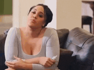 a woman is sitting on a couch with her arms crossed and a bottle of lotion in her hand .