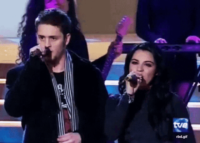 a man singing into a microphone next to a woman who is singing