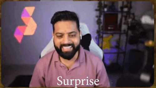 a man with a beard is sitting in a chair with the word surprise written on the screen behind him .