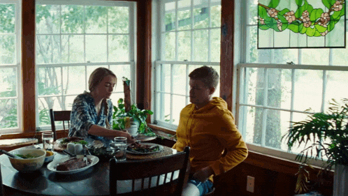 a man and a woman sit at a table with food