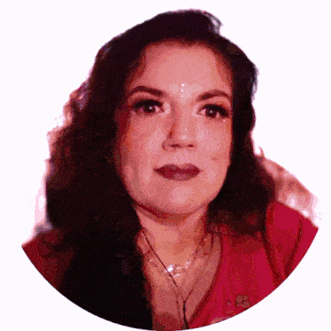 a woman in a red shirt with a necklace around her neck looks at the camera