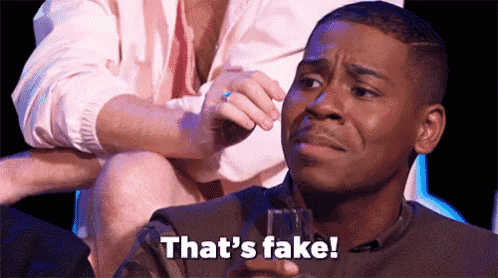 a man is sitting down with a glass in his hand and saying that 's fake .