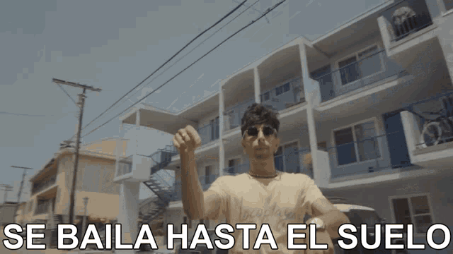 a man is standing in front of a building with the words se baila hasta el suelo written below him