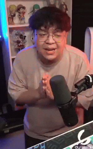 a man wearing glasses is standing in front of a microphone with the letter c on the bottom right