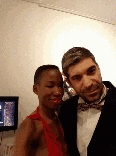 a man and woman pose for a picture in front of a tv