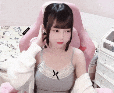 a girl is sitting in a pink chair with a cat ear headband