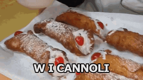 a tray of cannoli with powdered sugar and cherries and the words wi cannoli below them