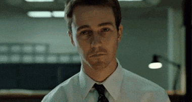 a man in a white shirt and tie is looking at the camera in an office .