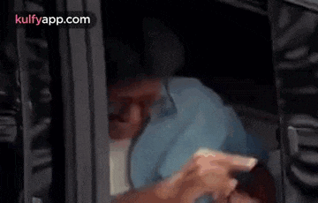 a man is sitting in a car looking out the window and making a funny face .