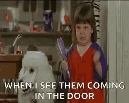 a little girl is standing next to a white poodle holding a broom .