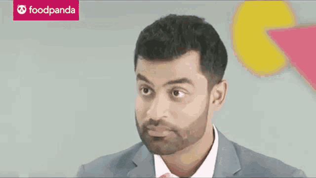 a man in a suit and pink shirt with a foodpanda logo in the background