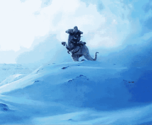 a man is riding on the back of an elephant on top of a snow covered hill