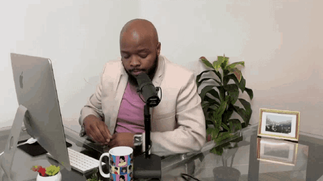 a man sits at a desk with a microphone and a computer