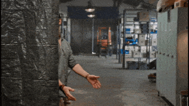 a man is standing in a warehouse with his hand outstretched