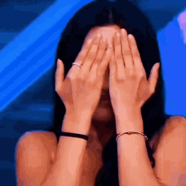 a woman is covering her face with her hands