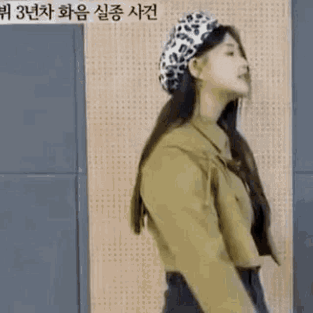 a woman wearing a leopard print beret and a crop top is standing in front of a wall .