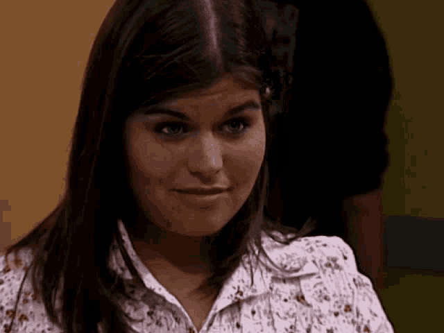 a woman wearing a floral shirt is making a face