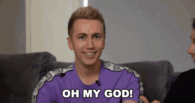 a young man in a purple shirt is smiling and says oh my god