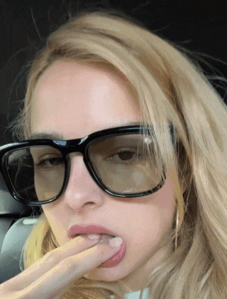 a close up of a woman wearing sunglasses and licking her lips