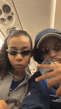 a man and a woman wearing sunglasses are taking a picture on an airplane