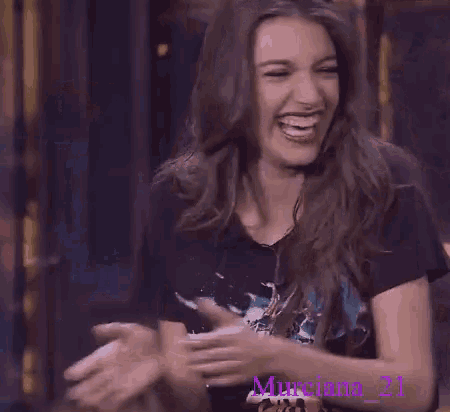a woman wearing a black shirt is laughing and has the number 21 on her shirt