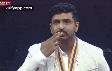 a man with a medal around his neck is blowing his nose .