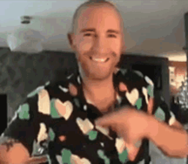 a man in a hawaiian shirt is smiling and dancing in a room .