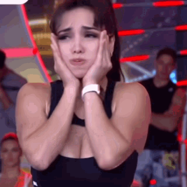 a woman is covering her face with her hands in a gym .