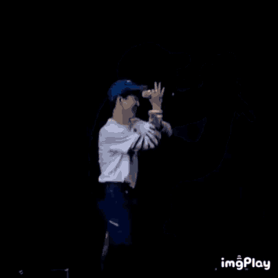 a man wearing a blue hat is singing into a microphone