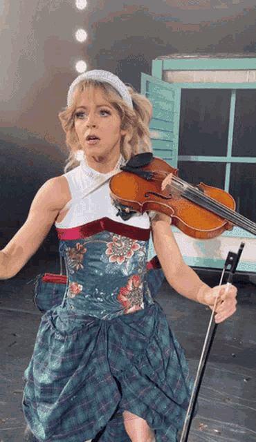 a woman in a plaid dress is playing the violin