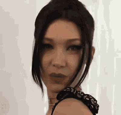 a close up of a woman 's face with long black hair and a choker around her neck .