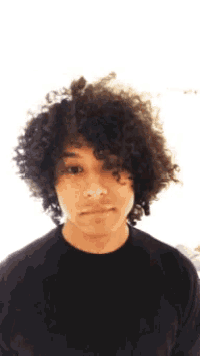 a young man with curly hair is wearing a black sweater