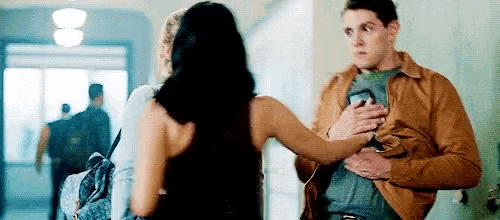 a man and a woman are standing next to each other in a hallway and the woman is hugging the man .