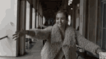 a woman in a fur coat is standing in a hallway