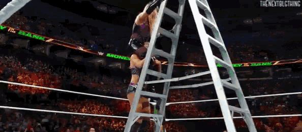 a woman climbs a ladder in a wrestling ring with the nextblcthing on the bottom right
