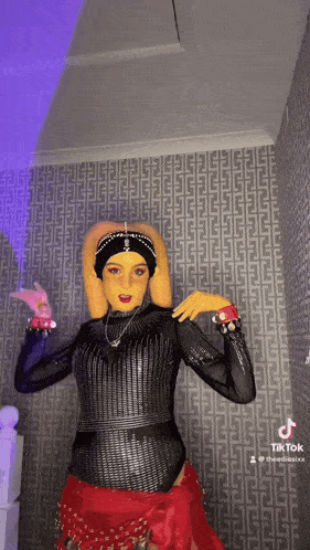 a woman in a costume is dancing in front of a patterned wall .